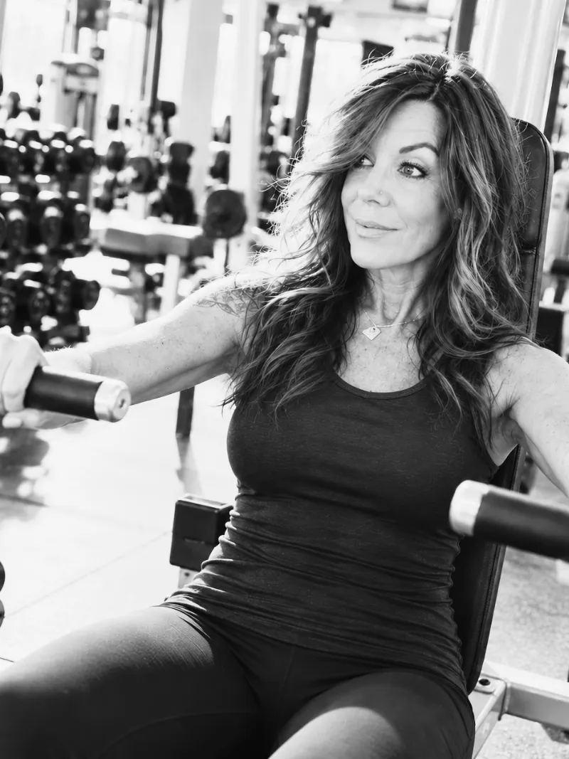 Lisa smiling between sets on a chest press machine at the gym